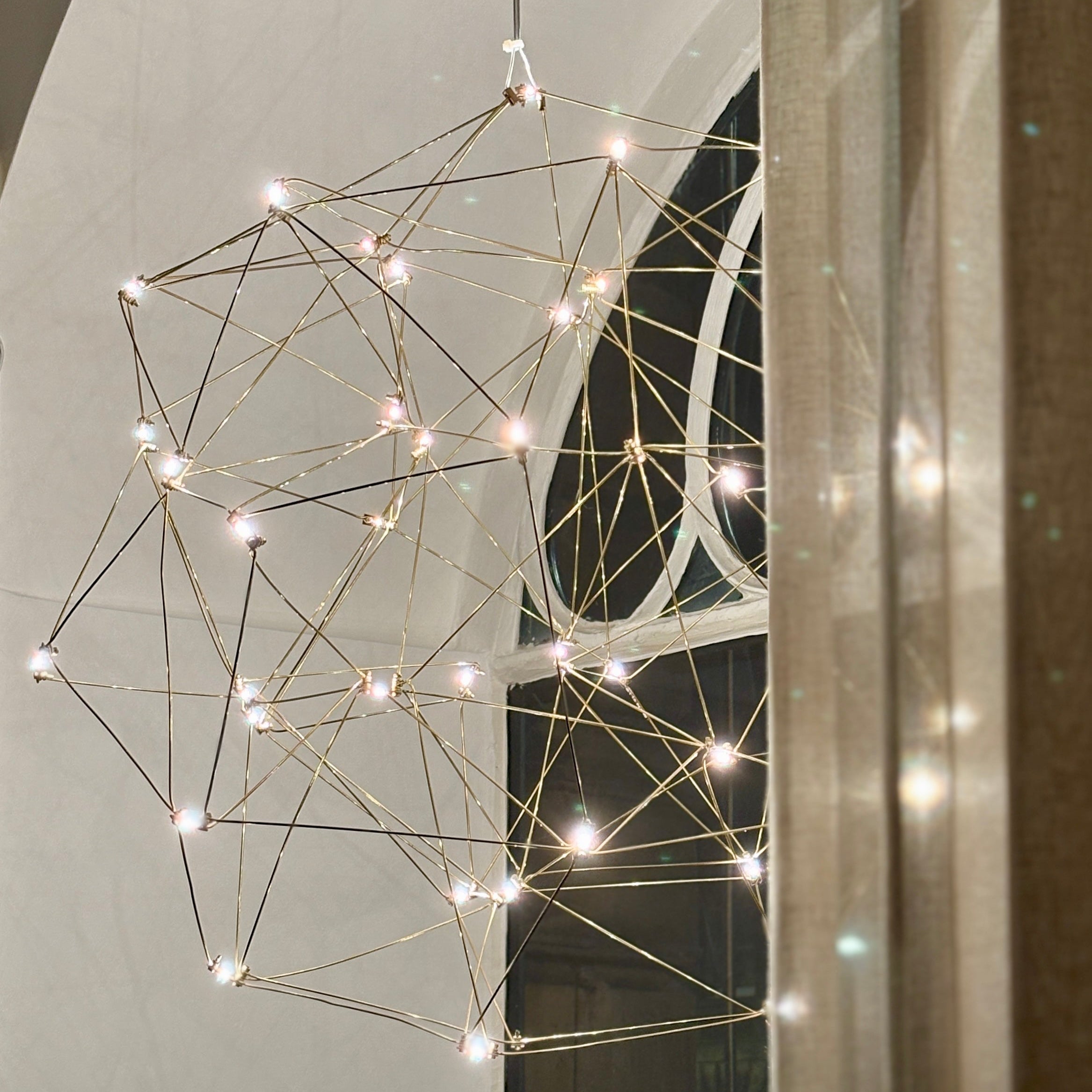 Geometric light fixture with string lights on a wall